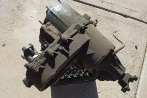 Dirty greasy transfer case from a 4x4 SUV sits on a driveway.